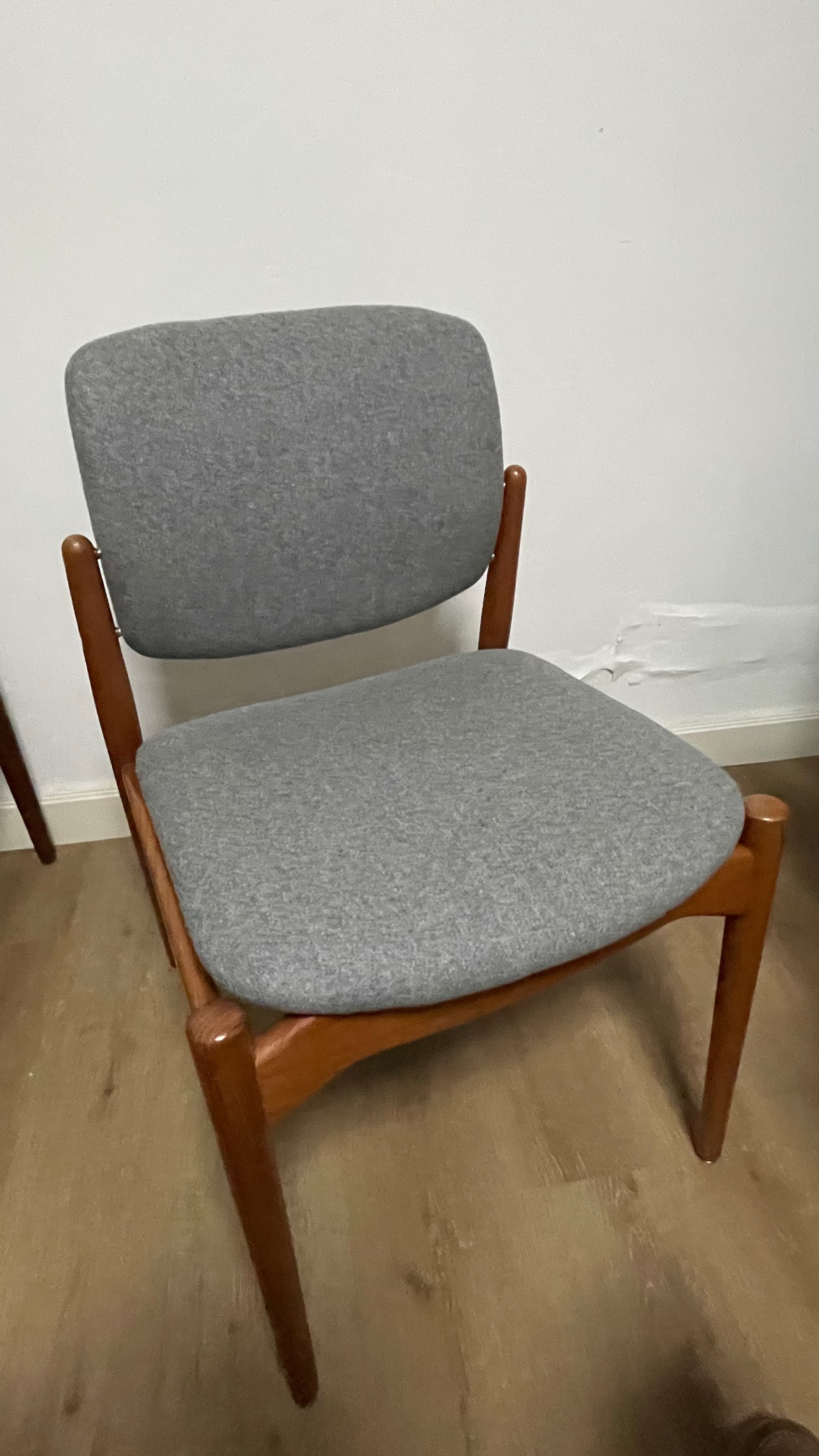 An armless dining chair featuring a minimalist design with a visible wooden frame and upholstered seat and backrest. The frame appears to be made of a warm-toned wood, possibly teak, with tapered legs. Both the seat and the slightly curved backrest are upholstered in a light grey fabric, providing a clean and contemporary aesthetic often associated with Scandinavian or Mid-Century Modern design. — 3D model
