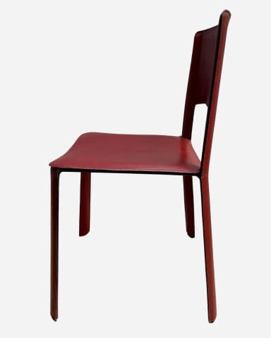 A modern, armless chair with a minimalist design. The seat and backrest are upholstered in a continuous piece of material that wraps around the frame. The chair features a cutout in the backrest for a modern aesthetic. The legs are straight and integral to the overall structure. Visible stitching around the edges of the seat and backrest indicates careful construction. — 3D model