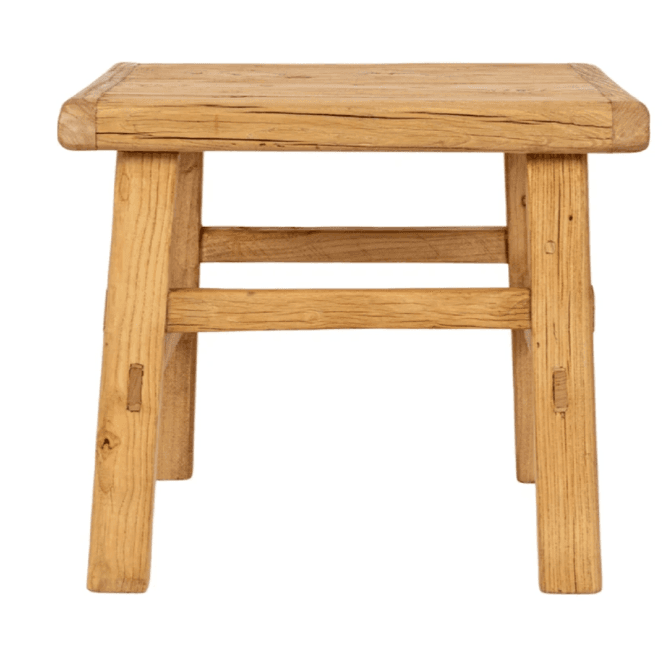 A rustic square stool constructed from what appears to be reclaimed wood, featuring a natural, light brown finish. The design is simple and sturdy, with a thick square top and four robust legs connected by stretchers on two sides. Visible joinery and the natural imperfections of the wood contribute to its aged and primitive aesthetic. — 3D model