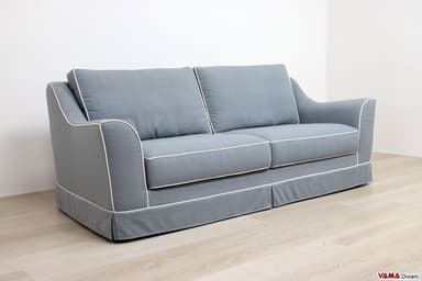 A two-seater sofa with plush cushions and a skirted base. The sofa features a light-colored fabric upholstery with contrasting green piping along the edges of the cushions, arms, and base. The armrests have a gently curved silhouette. — 3D model
