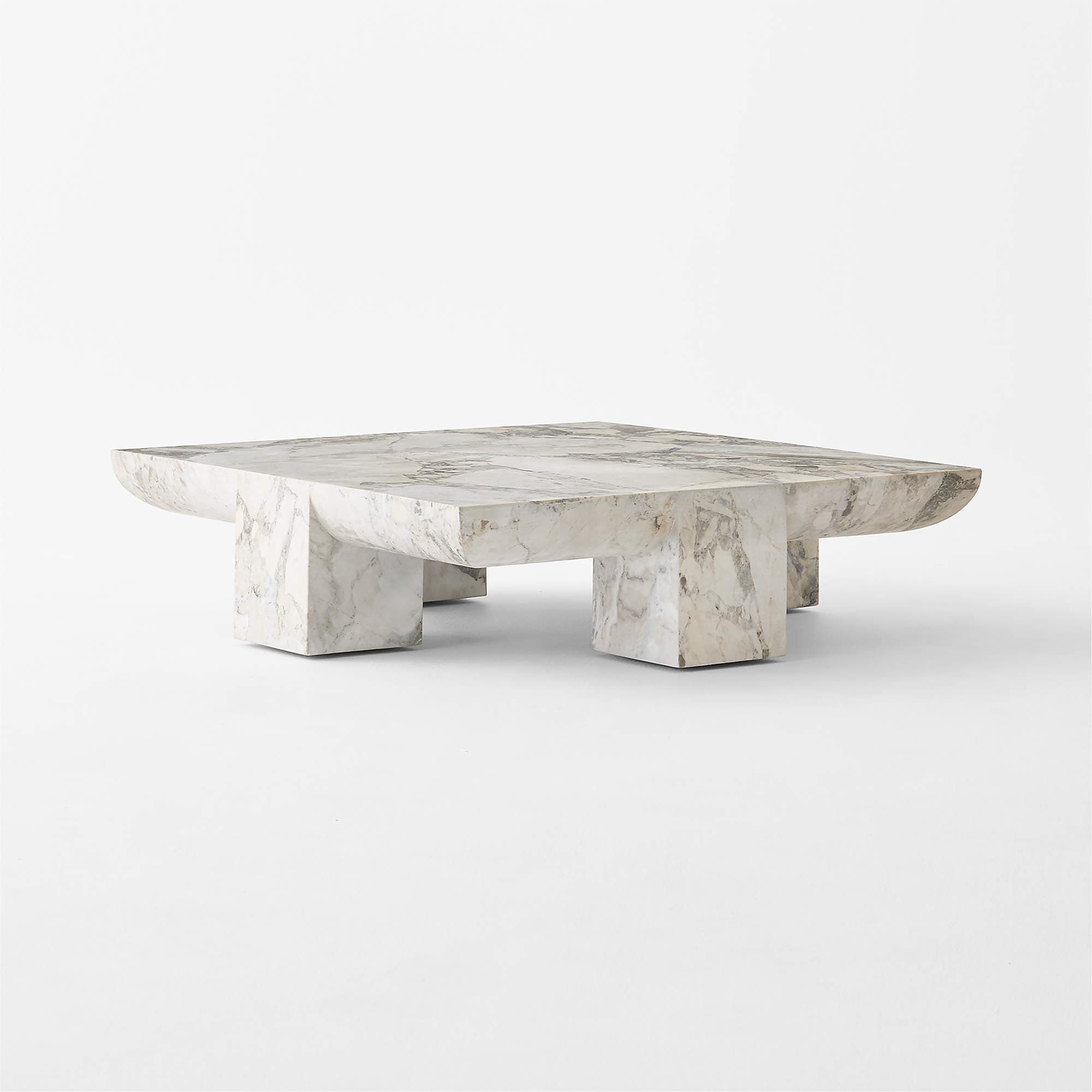 A square, low-profile coffee table constructed entirely from a light-colored marble with prominent grey veining. It features a substantial tabletop with subtly curved edges, supported by four solid, block-like legs that integrate seamlessly with the top. The design is minimalist and sculptural. — 3D model
