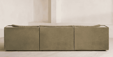 A long, contemporary sofa with a channeled upholstery design. The sofa features a modular appearance with distinct sections, creating a sense of depth and texture. It has a low profile and a deep seat, with curved armrests or side panels. A small, dark wood-toned surface is visible on the far left side, integrated into the structure. — 3D model