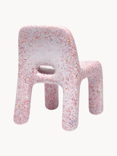 A small, child-sized chair made entirely from a single molded piece of recycled plastic, featuring a distinctive speckled or confetti-like pattern. The chair is predominantly white with multi-colored fragments (red, orange, yellow, blue, green) embedded throughout the material. It has a simple, monolithic design with rounded edges and a backrest, and an oval cutout in the seat. — 3D model