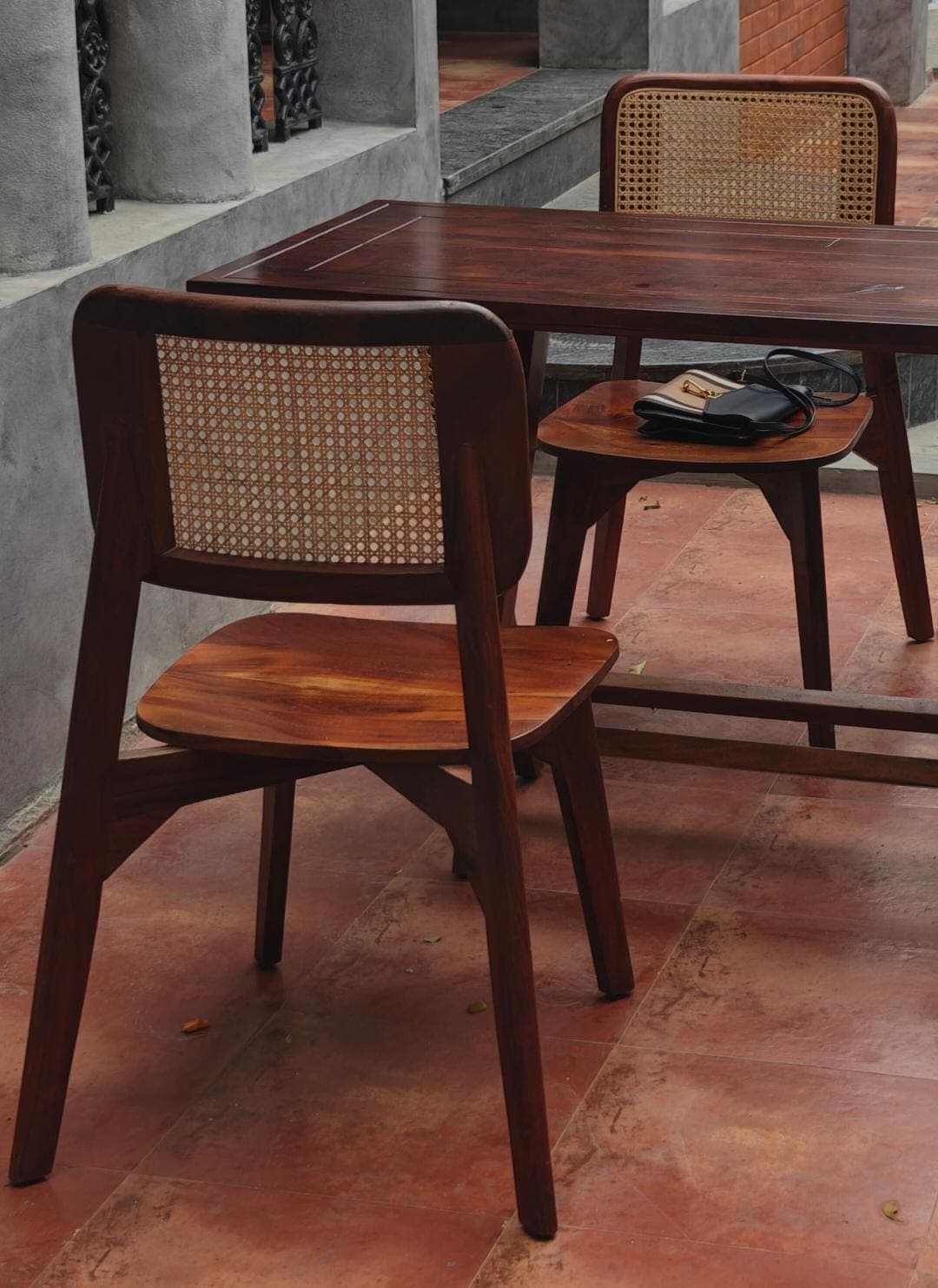 A contemporary dining chair featuring a solid wood frame with a rich walnut tone and a natural cane backrest. The design has a distinctive mid-century modern aesthetic with clean lines and subtly tapered legs. — 3D model