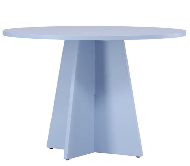 A light blue round dining table featuring a solid circular top supported by a distinctive pedestal base. The base is composed of four trapezoidal panels that converge towards the center, creating a sturdy and sculptural foundation. The entire table is finished in a uniform, matte pastel blue color, giving it a contemporary and minimalist aesthetic. Small black foot glides are visible at the bottom of each panel. — 3D model