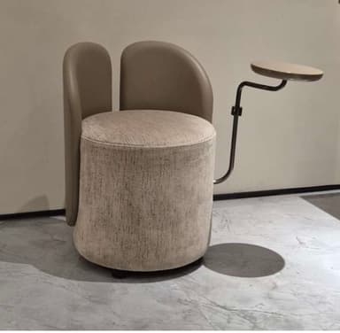 A modern, compact upholstered chair featuring a cylindrical base and seat, twin curved backrest panels, and an integrated swivel table attached via a sleek metal arm. — 3D model