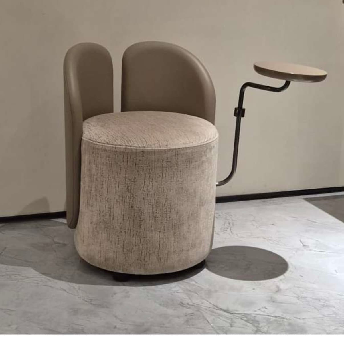 A modern, compact upholstered chair featuring a cylindrical base and seat, twin curved backrest panels, and an integrated swivel table attached via a sleek metal arm. — 3D model