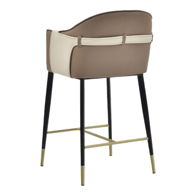 A contemporary bar stool featuring a two-tone upholstered seat and backrest with integrated armrests. The upholstery combines tan and cream tones, accented by a decorative strap on the back. It stands on tapered black metal legs with brass-finished footrests and leg caps. — 3D model