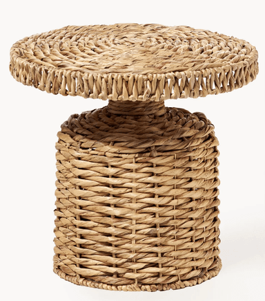 A small, round pedestal accent table crafted entirely from woven natural fibers, likely seagrass or water hyacinth. It features a solid cylindrical base that tapers slightly towards a smaller central column, which supports a thick, round tabletop. The weaving exhibits varying patterns, with a tighter, spiraled weave on the tabletop and a more open, basket-like weave on the cylindrical base. The table has a natural, earthy tone. — 3D model