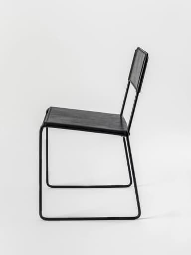 A contemporary armless chair featuring a minimalist design with a black metal sled frame and black leather upholstery for the seat and back. — 3D model