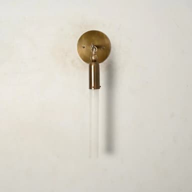 A modern wall sconce featuring a circular brass wall plate, an articulating arm, and a cylindrical brass housing holding a frosted glass rod-shaped shade. — 3D model