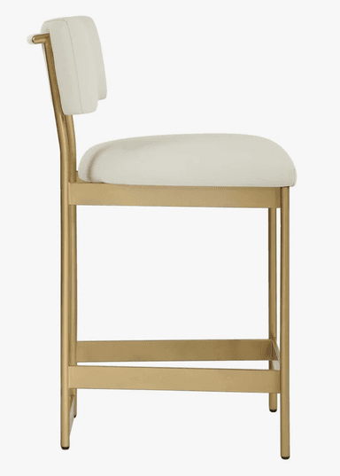 A modern bar stool featuring a gold-finished metal frame with a rectangular footrest and four legs. The seat and backrest are upholstered in a light, off-white or cream fabric/leatherette. The backrest is gently curved, and the frame extends up to support it. The overall design is sleek and contemporary. — 3D model