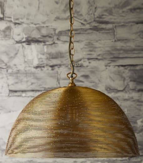 A dome-shaped pendant light featuring a shade constructed from tightly coiled or woven brass-toned metal wire. The wire creates a semi-transparent, textured surface that would diffuse light. The fixture is suspended by a matching metal chain, leading up to a ceiling mount (not fully visible). The metallic finish appears to be an aged or antique brass. — 3D model
