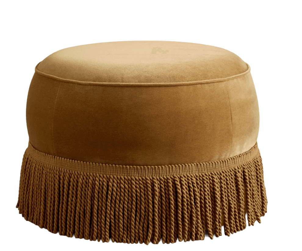 A round, upholstered ottoman with a plush velvet-like fabric in a warm golden-brown hue. The piece features a subtly domed top with piped edging. The lower portion of the ottoman is adorned with a thick, decorative fringe of twisted cords, extending to the base. The overall form is soft and inviting, with a classic yet opulent aesthetic. — 3D model