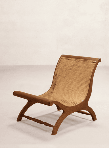 A low-slung, armless lounge chair featuring a dark stained wooden frame and natural cane webbing for both the seat and backrest. The frame exhibits curved profiles, contributing to a relaxed aesthetic. — 3D model
