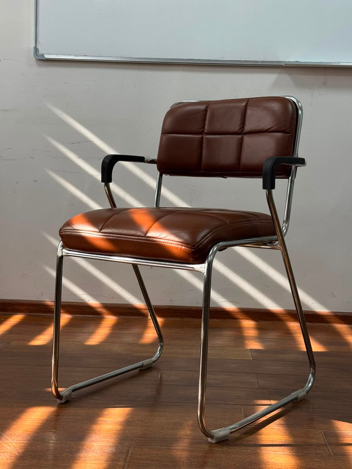 A mid-century modern style armchair featuring a polished chrome sled-base frame and brown quilted faux leather upholstery on the seat and backrest. — 3D model