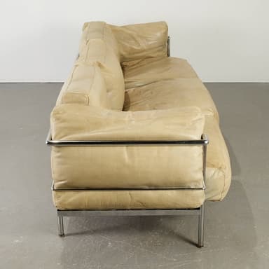 A sectional sofa with a light beige leather upholstery and a chrome frame. The sofa consists of multiple cushion modules, with the back cushions appearing somewhat unstructured and draped. The frame is visible on the sides and forms the legs of the sofa. The overall design suggests a modern or contemporary aesthetic. — 3D model