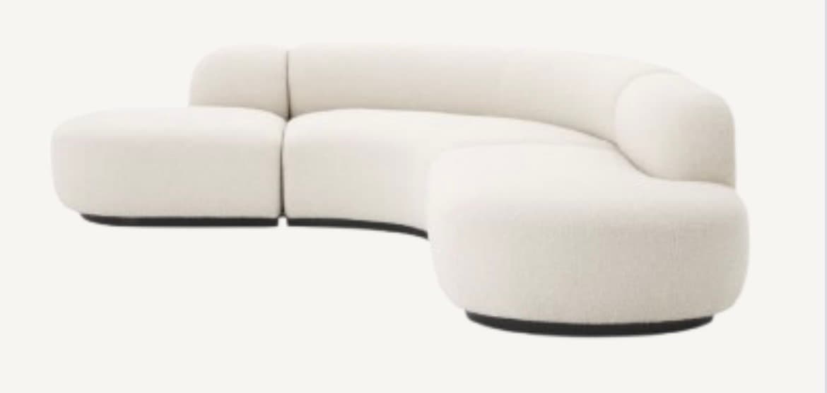 A modern, modular sectional sofa featuring a distinctive curved form and upholstered in a tactile, off-white boucle fabric. The sofa comprises multiple individual components that can be arranged to create various seating configurations. It has a low-profile design with rounded edges and soft, voluminous cushions, resting on a recessed dark base. — 3D model