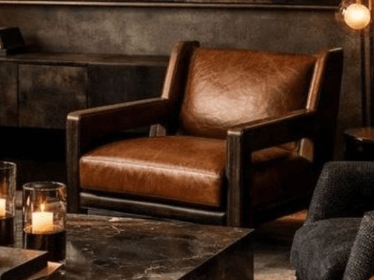 A contemporary armchair featuring a dark brown wooden frame with integrated armrests and legs, upholstered in rich brown leather on the seat, back, and arm cushions. The design has clean lines and a squared-off silhouette. — 3D model
