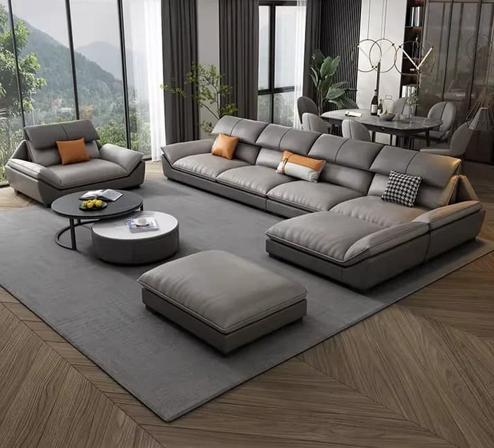 A modern multi-piece seating set featuring a large L-shaped sectional sofa with an integrated chaise lounge, a matching single armchair, and a rectangular ottoman. All pieces are upholstered in a two-tone grey material, likely faux leather, with plush seating and backrests. The backrests appear to have adjustable headrest sections. — 3D model