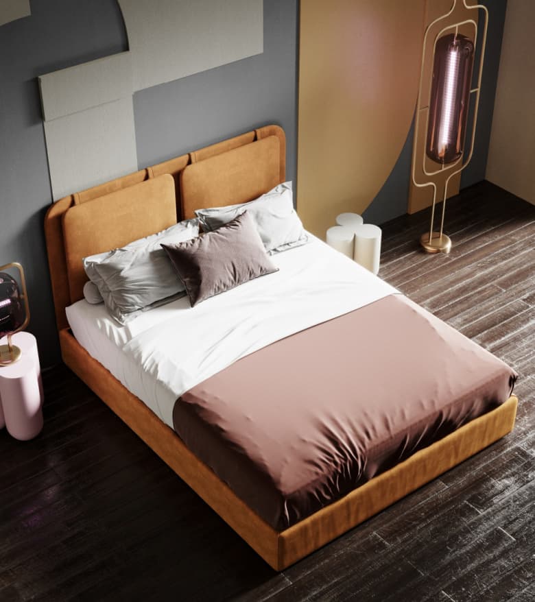 A low-profile upholstered bed frame with a rectangular headboard featuring two padded sections. The frame is covered in a textured, warm-toned fabric. The bed is dressed with white sheets, a dusty rose duvet or comforter, and several pillows, including two large grey ones and a smaller textured brown decorative pillow. — 3D model