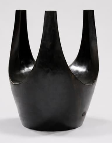 A dark, U-shaped sculptural stool, likely crafted from patinated bronze or ebonized wood. Its form is fluid and organic, with a deep, curved seat integrated into the continuous structure. The material exhibits a smooth, subtly reflective finish. — 3D model