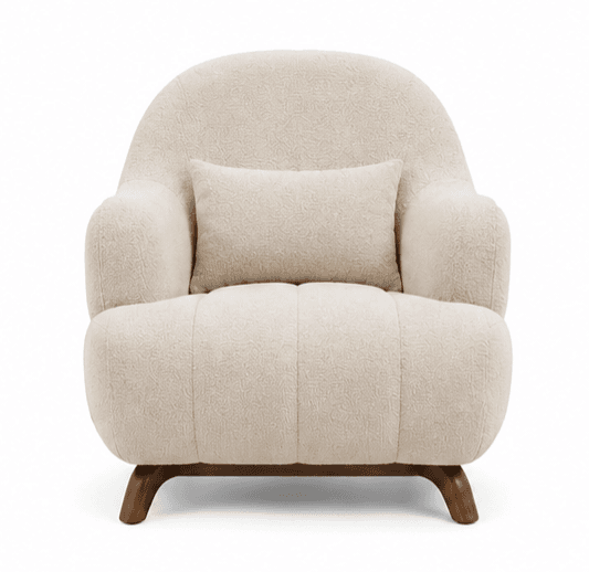 An upholstered armchair featuring a plush, rounded silhouette. The chair is covered in a textured cream-colored boucle fabric. It has integrated, softly curved arms and a continuous backrest. The seat base includes subtle vertical channel tufting. The chair rests on short, splayed dark wood legs. A matching rectangular lumbar pillow is included. — 3D model