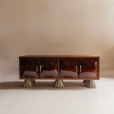 A long, rectangular sideboard featuring a walnut wood frame and top surface. The front is composed of four individual cabinet doors with a high-gloss, deep reddish-brown lacquered finish. Each pair of doors is equipped with two horizontal, silver-toned bar pulls. The entire cabinet is elevated on four distinctive, sculptural, conical legs with a fluted or pleated texture, appearing to be made from a light-colored composite or concrete material. The design combines classic wood elements with contemporary finishes and an abstract base. — 3D model