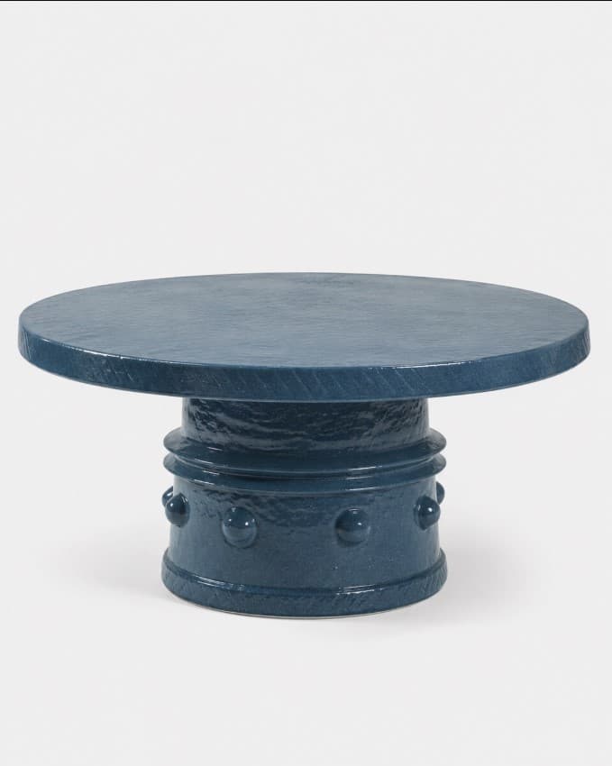 A contemporary, round coffee table featuring a robust, textured finish in a matte dark blue color. It has a thick, circular tabletop supported by a wide, cylindrical pedestal base. The base is decorated with a series of regularly spaced, spherical protrusions around its lower section, adding a distinctive tactile and visual element. The entire piece exhibits a monolithic and sculptural quality. — 3D model