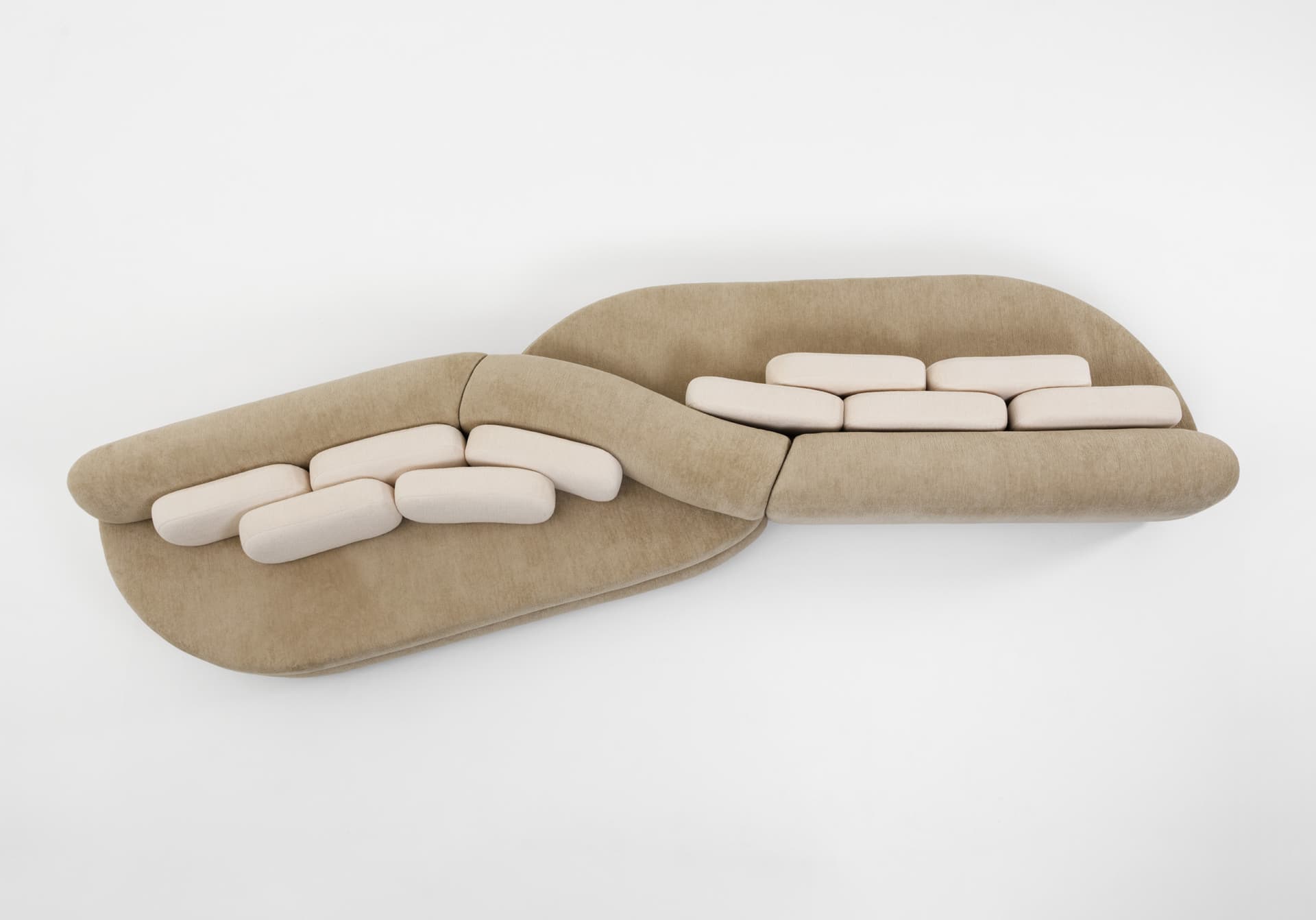 An aerial view of a contemporary two-piece modular sectional sofa featuring an organic, curvilinear shape. The primary upholstery is a textured, light brown or tan fabric. The sofa includes multiple, smaller, rectangular back cushions upholstered in a lighter, cream-colored fabric, arranged in rows on the backrests. The design emphasizes soft lines and a sculptural form. — 3D model