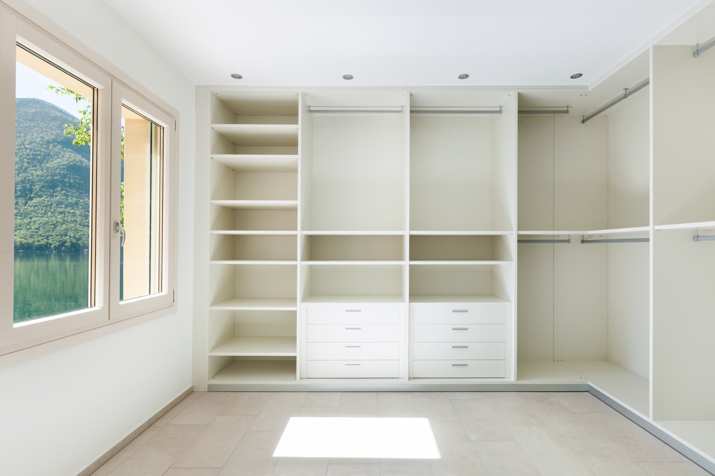 An L-shaped modular open closet system in a clean white finish, featuring a combination of open shelving compartments of various sizes and integrated drawers with minimalist handles. The unit is designed for corner placement and efficient organization of clothing and accessories. — 3D model