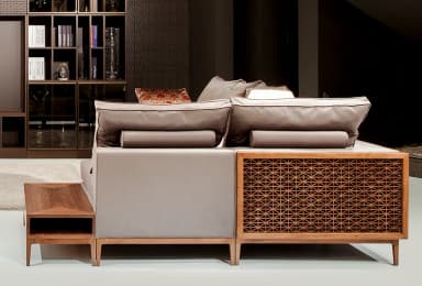 A modular sectional sofa with upholstered cushions and a decorative wooden side panel. The sofa has a low profile with slender wooden legs. It includes several plush throw pillows, one of which has an ornate patterned cover. A matching wooden coffee table with an open compartment is positioned in front of the sofa. — 3D model