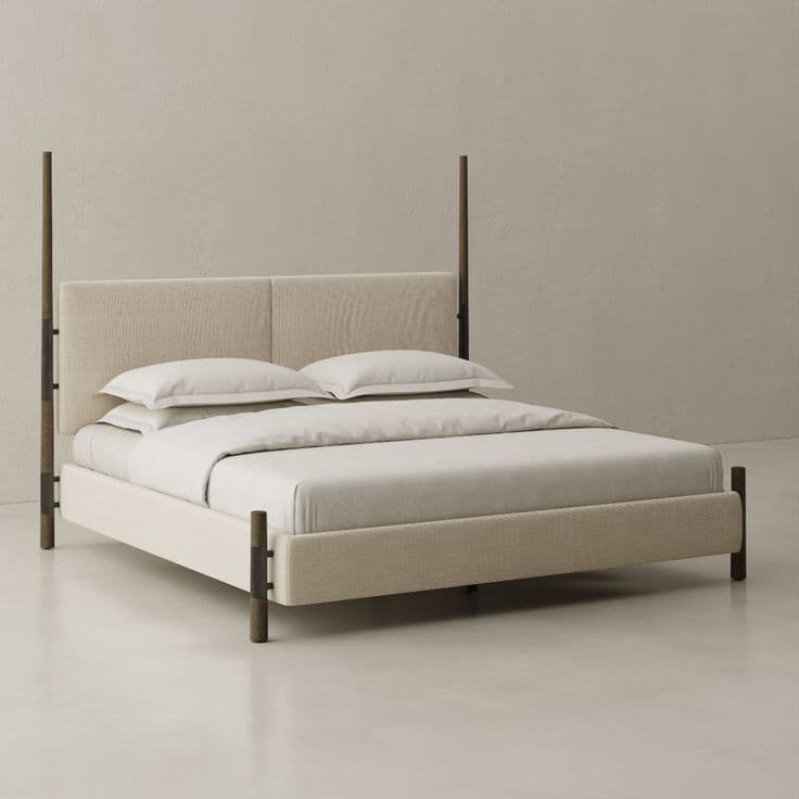 A modern upholstered four-poster bed featuring a minimalist design. The headboard and bed frame are fully upholstered in a light beige, textured fabric. Four slender, dark brown or black posts extend upwards from each corner, adding a subtle vertical element without forming a full canopy. The bedding is a simple, neutral white. — 3D model