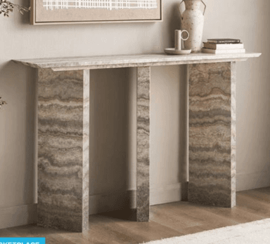 A long, narrow console table made entirely from a natural stone resembling travertine, characterized by its distinct banded patterns and earthy tones. The design is minimalist, featuring a rectangular top supported by two thick, rectangular slab legs. — 3D model