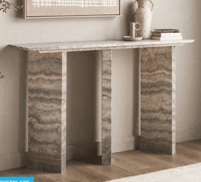 A long, narrow console table made entirely from a natural stone resembling travertine, characterized by its distinct banded patterns and earthy tones. The design is minimalist, featuring a rectangular top supported by two thick, rectangular slab legs. — 3D model