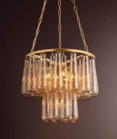 A contemporary tiered chandelier featuring a gold-finished metal frame and numerous textured, amber-toned glass shades. The fixture is suspended by a delicate chain from a matching ceiling canopy, with internal light sources illuminating the glass elements. — 3D model