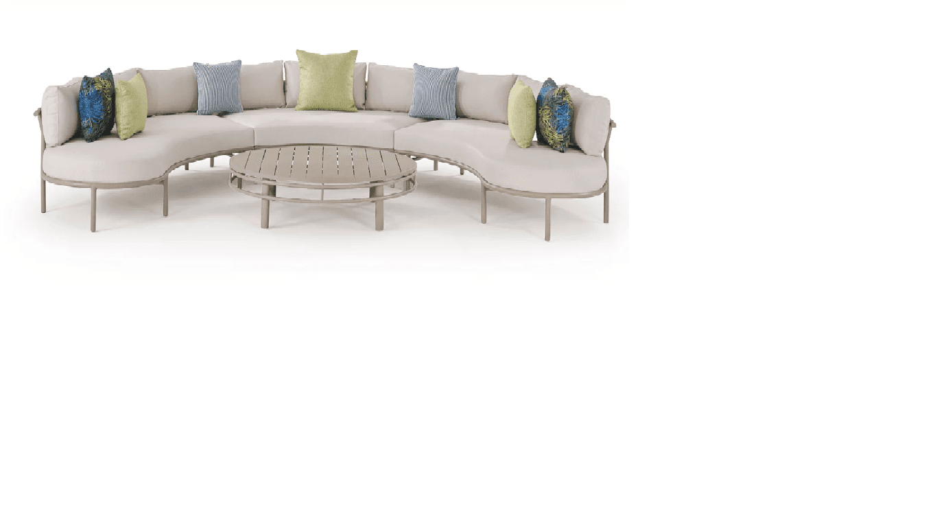 A contemporary outdoor furniture set comprising a large, curved modular sectional sofa and a matching round coffee table. The sofa features a light beige aluminum frame, plush light-colored cushions, and several accent pillows in blue, green, and patterned fabrics. The coffee table has a slatted top designed to complement the sofa's frame. — 3D model