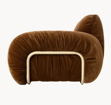 A plush, sculptural armchair upholstered in a rich brown velvet fabric. The armchair features an organic, rounded silhouette with ample cushioning that appears to be gathered or shirred, creating a textured effect. A tubular metal frame, finished in a light, possibly cream or off-white color, is visible beneath the upholstery, providing structural support and a contrasting element. The design evokes a contemporary, possibly retro-inspired aesthetic. — 3D model