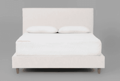 A minimalist upholstered platform bed featuring a rectangular headboard and a low-profile frame. The bed is covered in an off-white or cream-colored fabric and stands on four light-toned, tapered wooden legs. A mattress and two white pillows are present on the bed. — 3D model