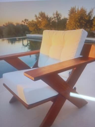 A modern lounge chair featuring a robust wooden frame and thick, tufted white cushions. The frame is constructed with wide, flat armrests and distinctive X-shaped side supports, creating a low-slung and sturdy profile. The design emphasizes comfort and a clean, contemporary aesthetic. — 3D model
