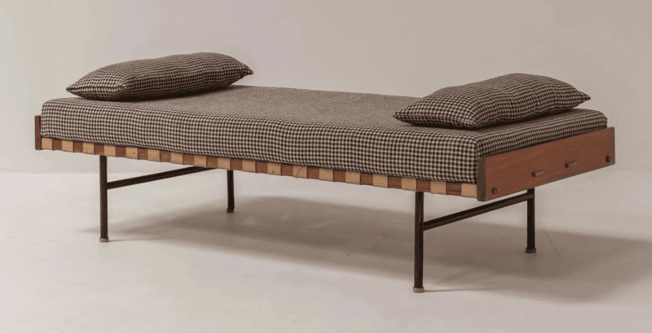 A mid-century modern daybed featuring a solid wood frame, black metal legs, a fabric-upholstered mattress, and two matching pillows. The mattress rests on a suspended base of woven light brown leather straps. One end of the wooden frame has a subtle recessed handle detail. — 3D model