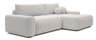 A sectional sofa with a plush, textured fabric upholstery. The sofa features a low profile, deep seating, and square arms. It is configured as an L-shape, with a longer section on the left and a shorter chaise or extension on the right. Two spherical throw pillows with the same fabric are placed on the right section. The sofa is supported by short, dark-colored legs. — 3D model