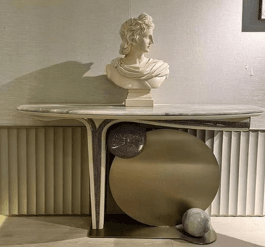 An elegant and sculptural console table featuring a grey and green veined marble top with an asymmetrical, curved edge. The base is crafted from polished gold-toned brass, forming a dynamic composition of geometric shapes, including a large circular disc, vertical ribbed elements, and a small marble sphere at its base, creating a distinctive Art Deco-inspired aesthetic. — 3D model