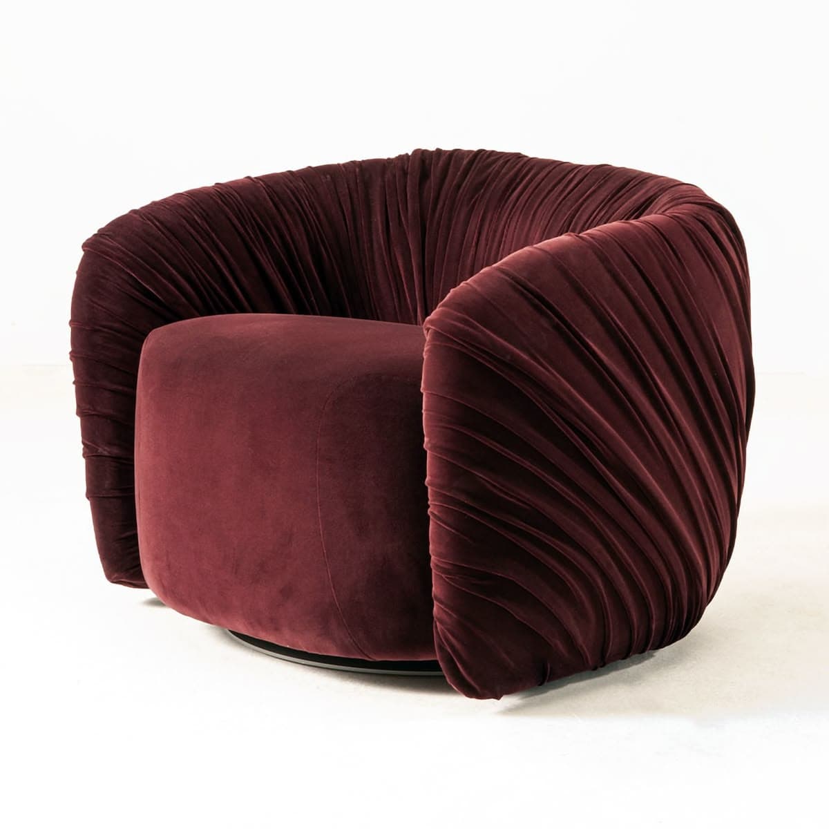 A contemporary lounge chair featuring a rich burgundy velvet upholstery with distinctive, extensive pleating across its curved back and armrests. The chair has a barrel-like form, providing an enveloping and comfortable seating experience. Its base is a discreet, dark-colored swivel mechanism, allowing for rotation. The internal seat cushion is smooth velvet, contrasting with the textured exterior. The overall design exudes a luxurious and modern aesthetic. — 3D model