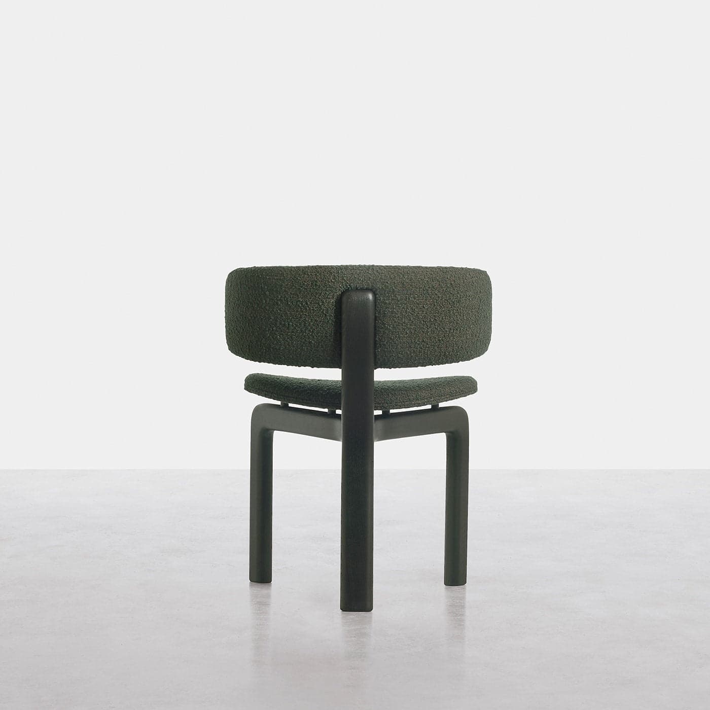 A contemporary armless chair featuring a thick, rounded backrest and seat cushion upholstered in a textured dark green fabric. The frame is constructed from substantial, dark-colored rectangular legs and a supporting structure that integrates the backrest, contributing to a sturdy and minimalist design. — 3D model