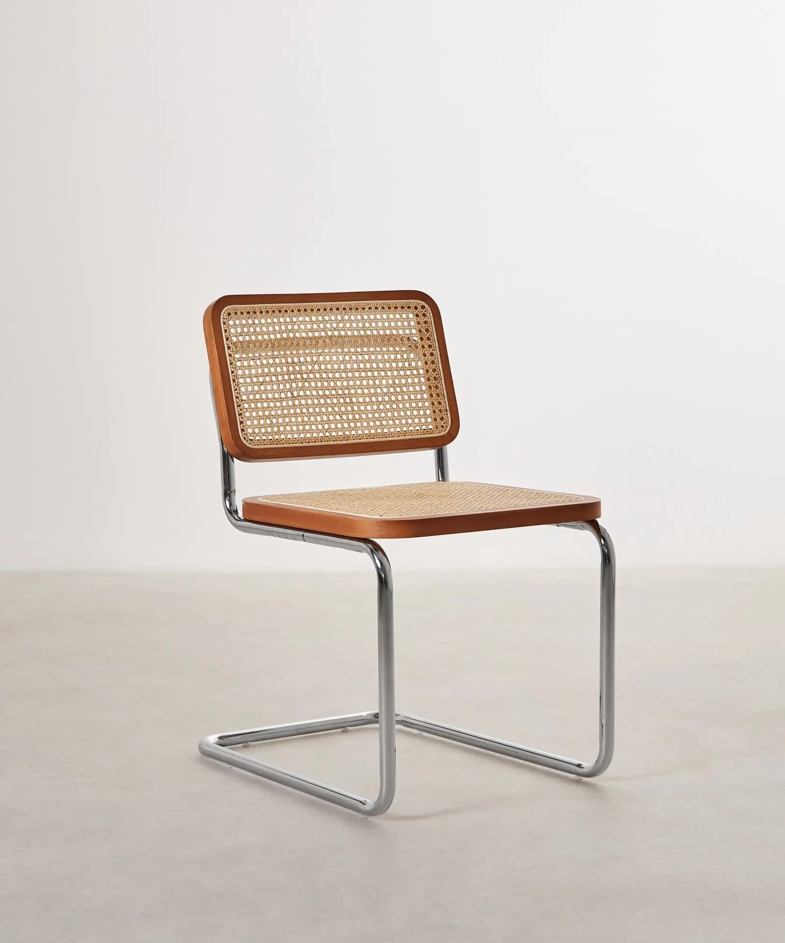 An armless modern cantilever side chair featuring a polished chrome tubular steel frame and a seat and backrest constructed from wooden frames with natural cane webbing inserts. The chair exhibits a sleek, minimalist aesthetic. — 3D model