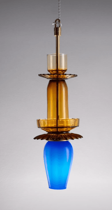 A visually striking pendant light featuring multiple stacked glass elements in amber and blue, accented with brass. The design incorporates fluted glass details and a central brass stem for suspension. — 3D model