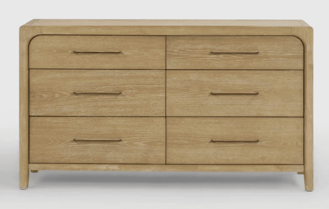 A rectangular six-drawer dresser made from light-toned oak wood with prominent grain. It features softly rounded vertical corners on the frame, and minimalist dark metal bar pulls on each drawer. The dresser stands on short, integrated legs. — 3D model