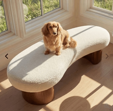 A modern bench featuring an organically shaped, off-white bouclé upholstered seat supported by two sturdy, cylindrical dark wood legs. — 3D model