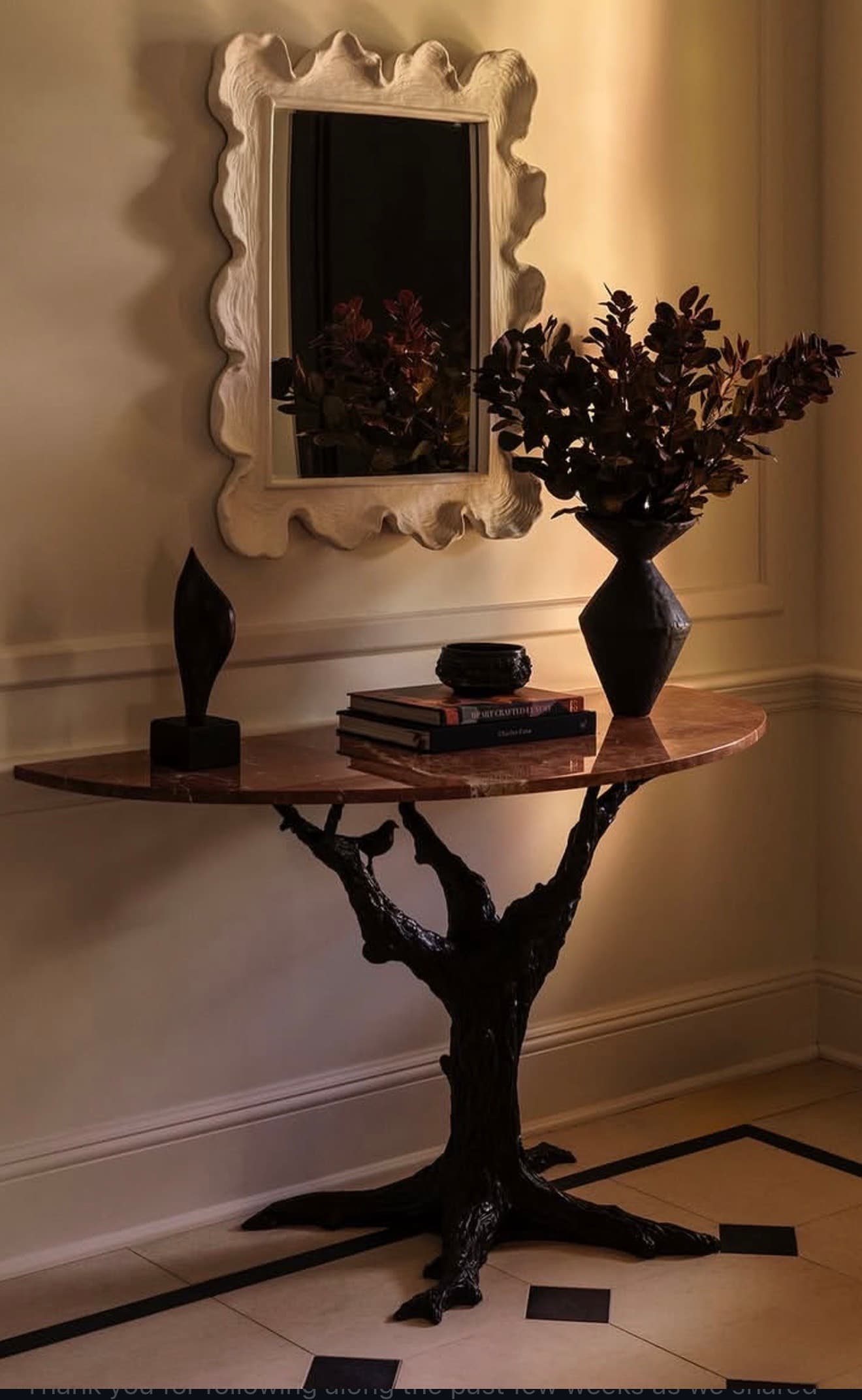 A sophisticated demilune (half-round) console table featuring a polished pink marble top with natural veining. The table is supported by a highly sculptural base crafted from dark bronze-toned metal, designed to resemble intertwining tree branches and roots. A small, dark abstract sculpture is placed on the tabletop. — 3D model